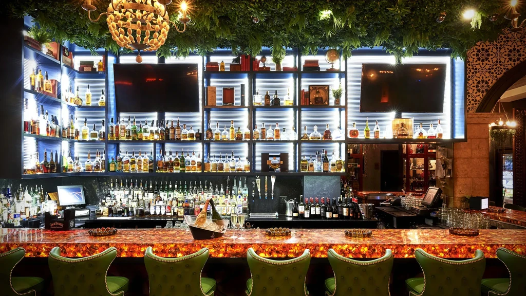 Sophisticated bar with backlit liquor shelves and a glowing orange counter.