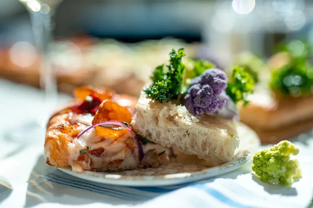 Two small plates: cheesy bread, purple cauliflower with green leaves.