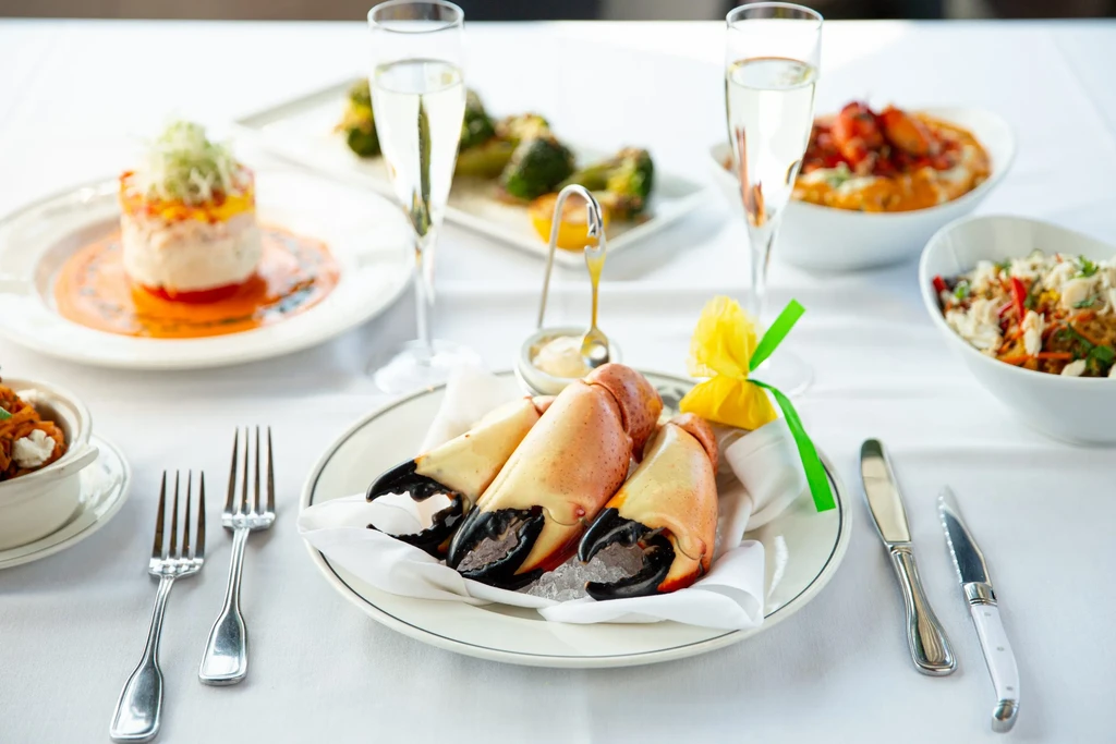 Upscale restaurant table with stone crab claws, layered appetizer, and champagne.
