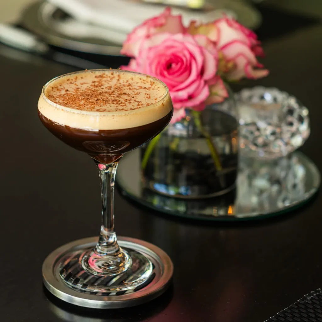 Two-toned espresso martini in coupe glass with foam and chocolate shavings.