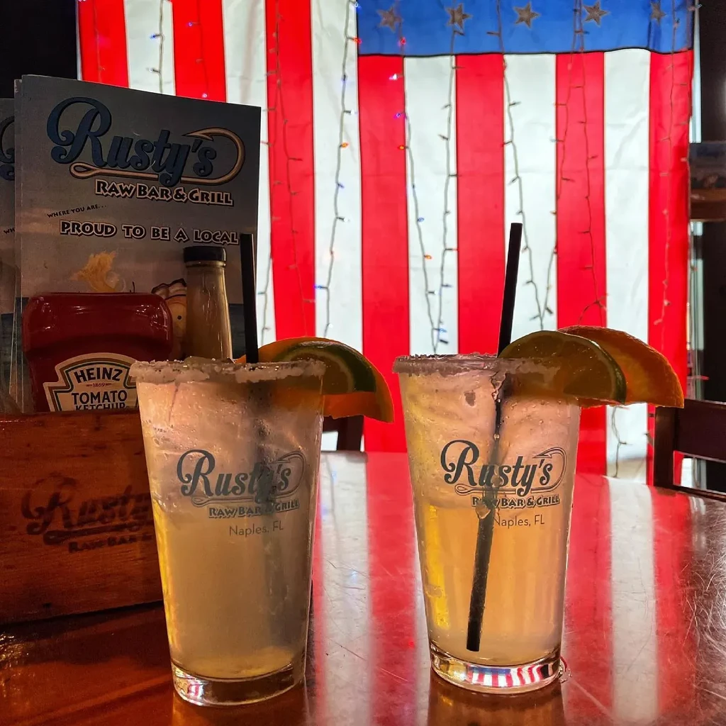 Frosty Rusty's cocktails with citrus garnish, American flag background.