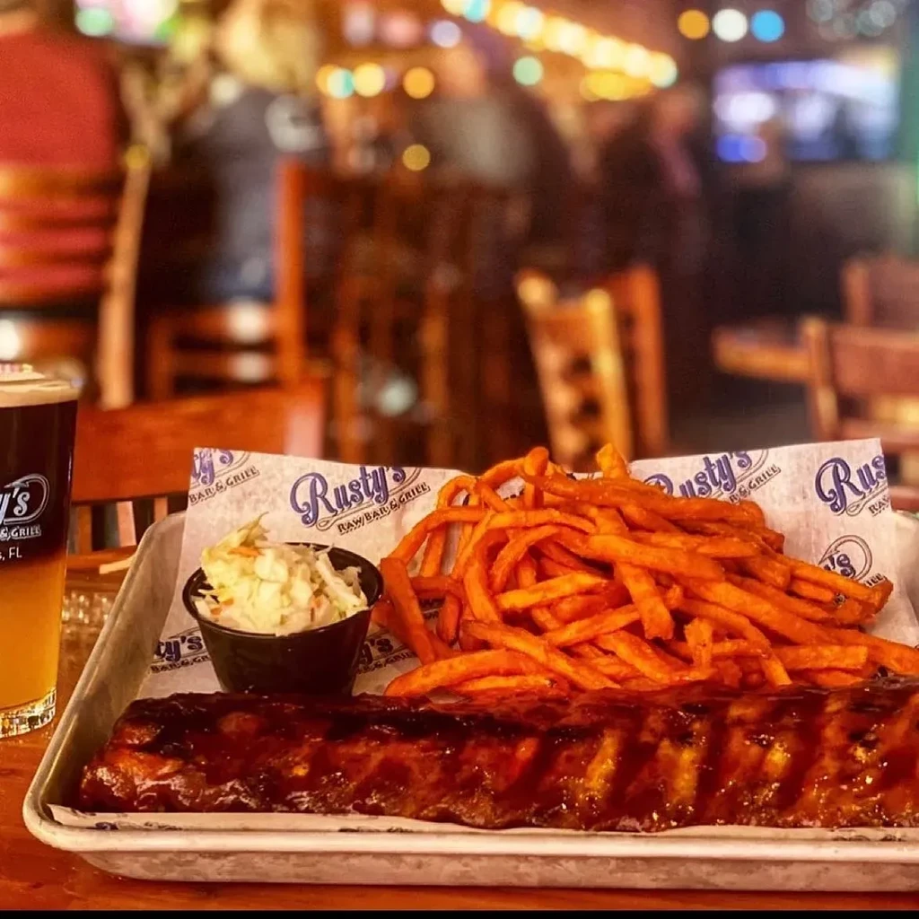 Full rack of barbecue ribs, sweet potato fries, coleslaw, and branded beer.