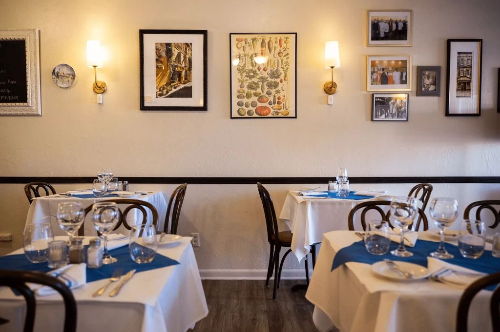 Warmly lit restaurant dining area with set tables and bentwood chairs.