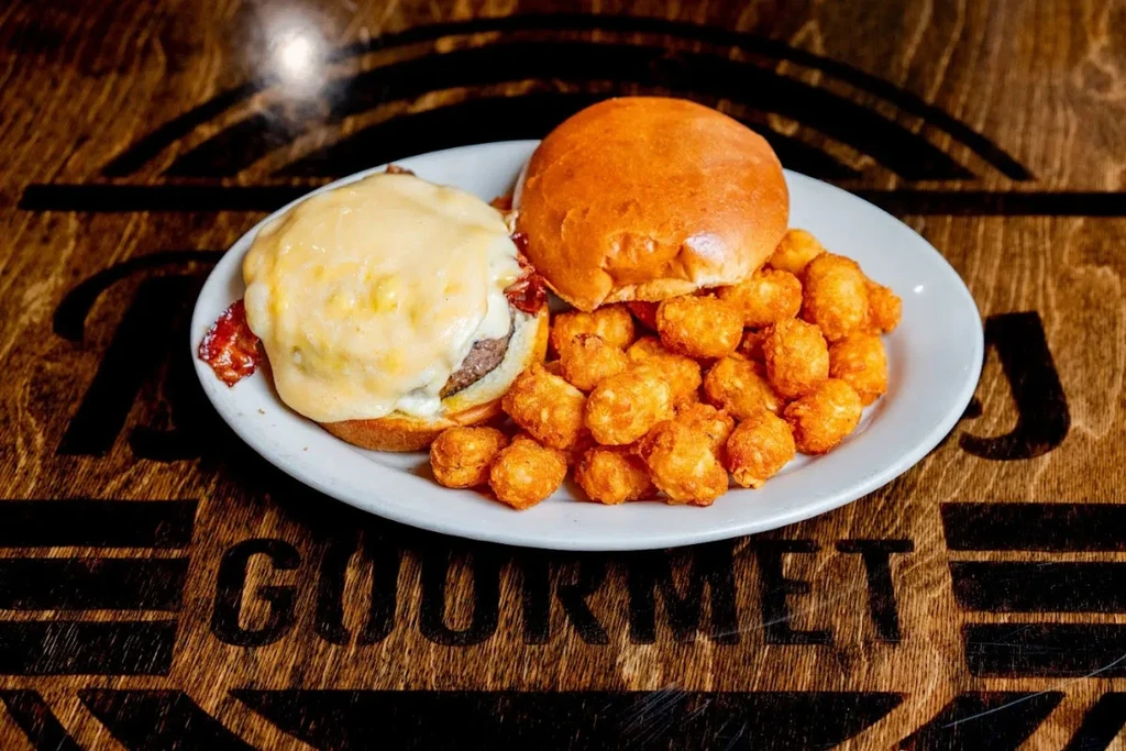 Open-faced bacon cheeseburger with melted cheese and crispy tater tots.