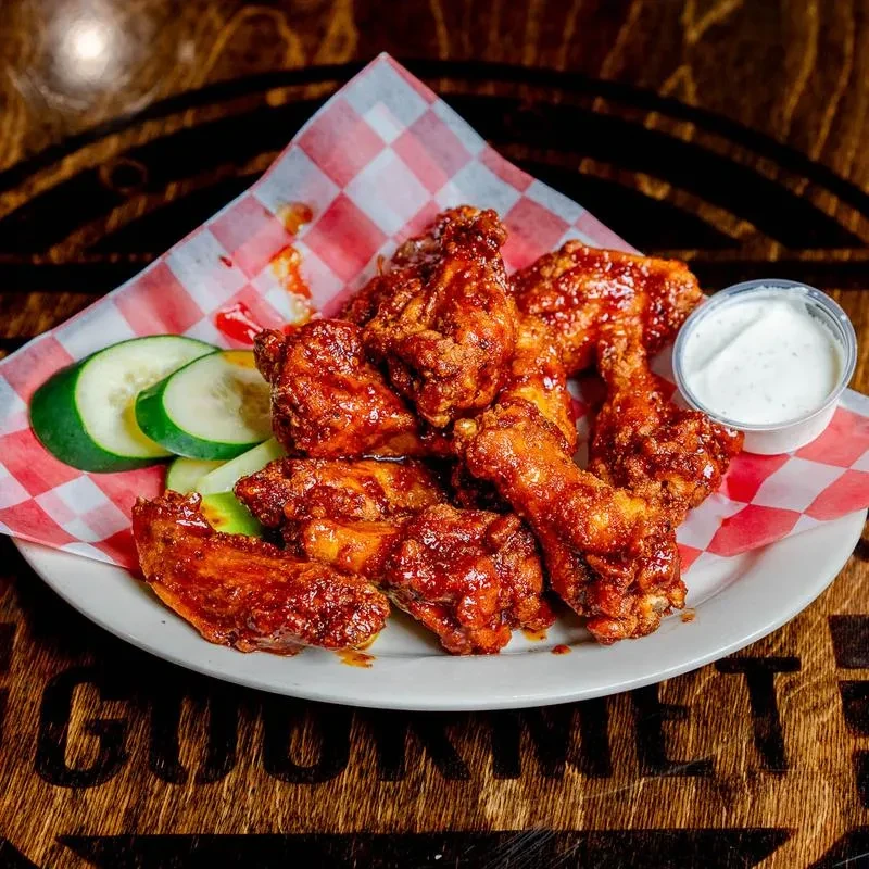 Plate of glossy chicken wings, cucumber slices, and white dipping sauce.