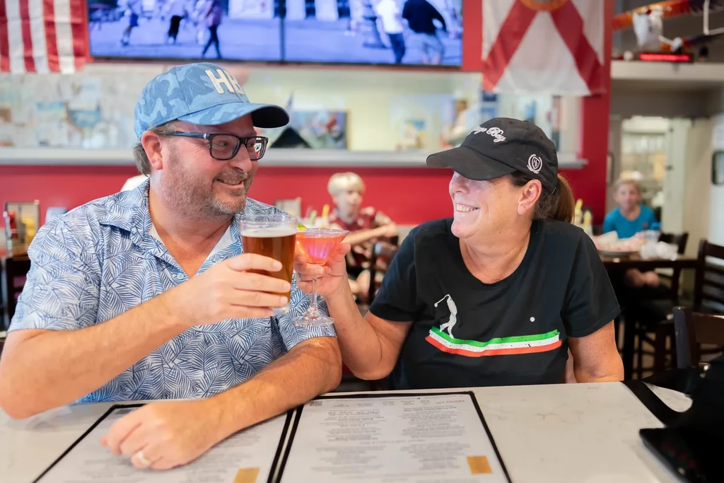 Smiling man and woman clink drinks in a restaurant toast.