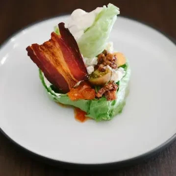 Crisp wedge salad with crispy bacon, creamy dressing, and tomatoes.