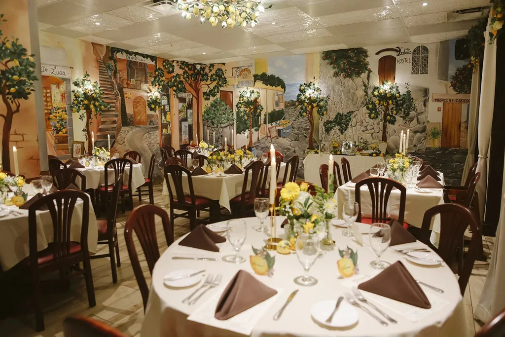 Formal restaurant with Italian village mural and lemon-themed decor.