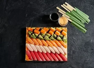 Vibrant overhead shot of sushi and sashimi platter with sauces and chopsticks.