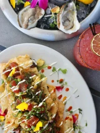 Overhead: oysters on ice, tuna flatbread, and a pink cocktail.