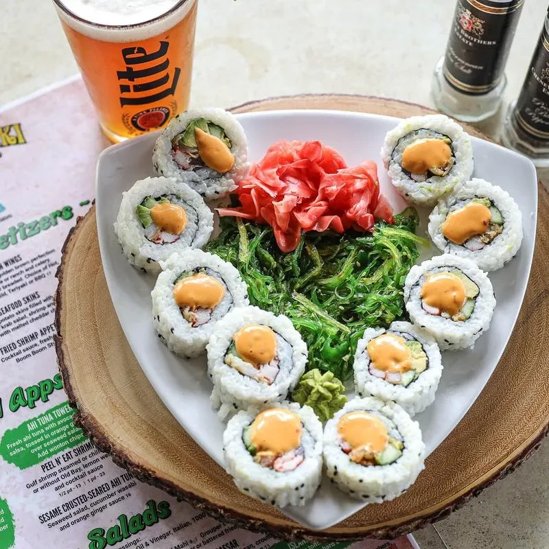Top-down view of maki sushi, Miller Lite beer, seaweed salad, and menu.
