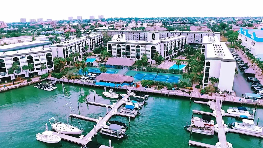 Aerial view of a vibrant waterfront resort with marina, pools, and tiki huts.