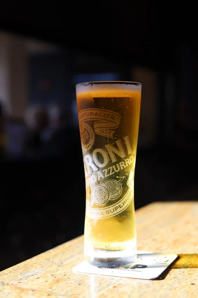 Peroni beer in an etched glass on a light stone counter.