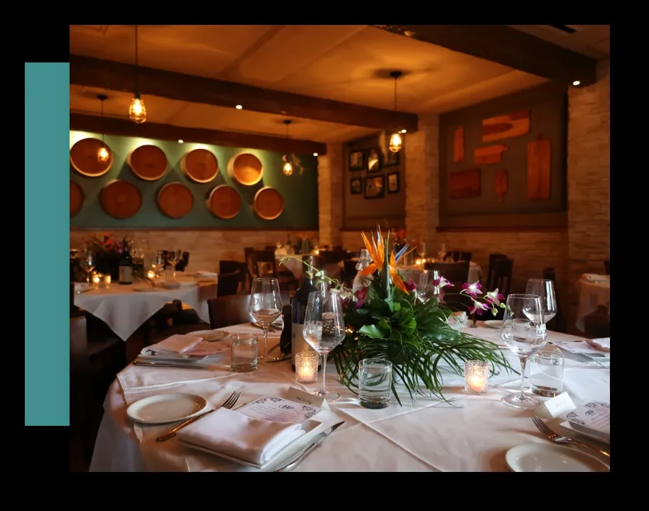 Dimly lit upscale restaurant with a set table and vibrant floral centerpiece.