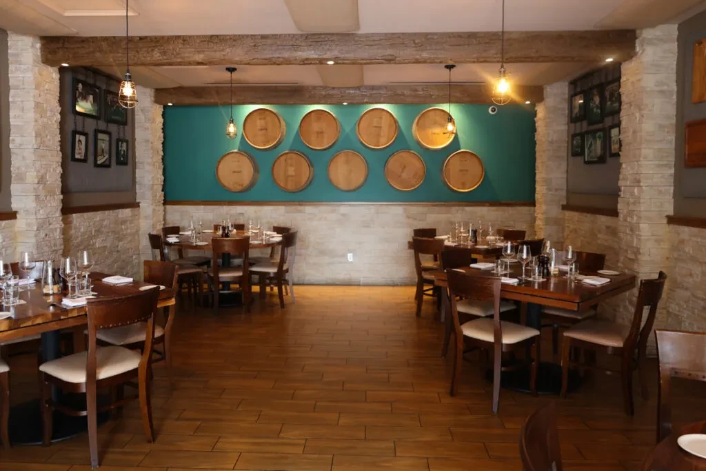 Empty rustic-chic restaurant dining room with teal barrel accent wall.