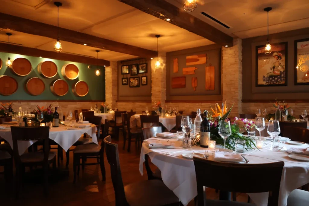 Dimly lit, rustic-chic restaurant dining room with elegantly set tables.