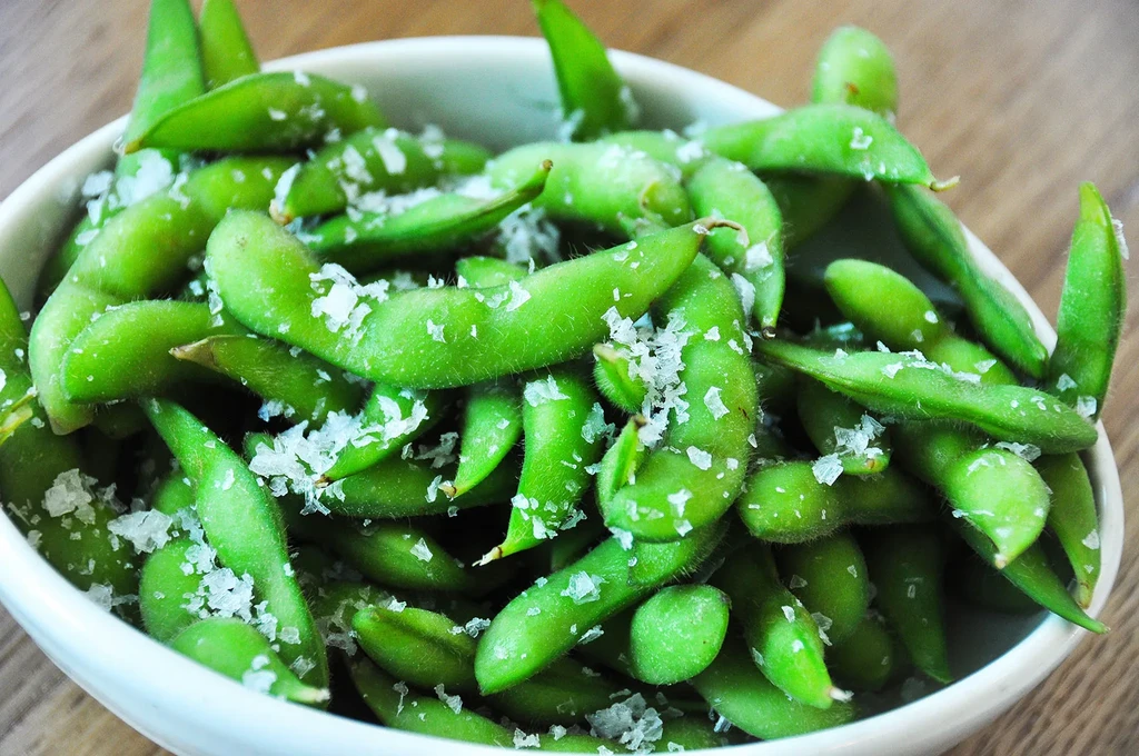 Bright green edamame pods in a bowl, generously sprinkled with sea salt.