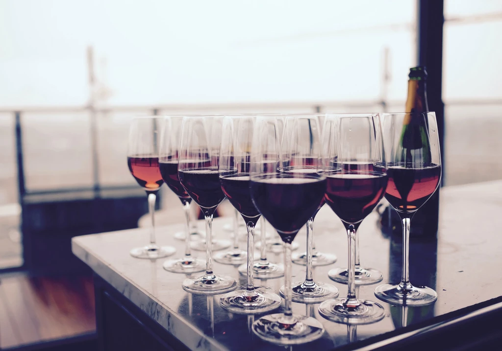 Row of wine glasses with red and rosé wine on a marble counter.