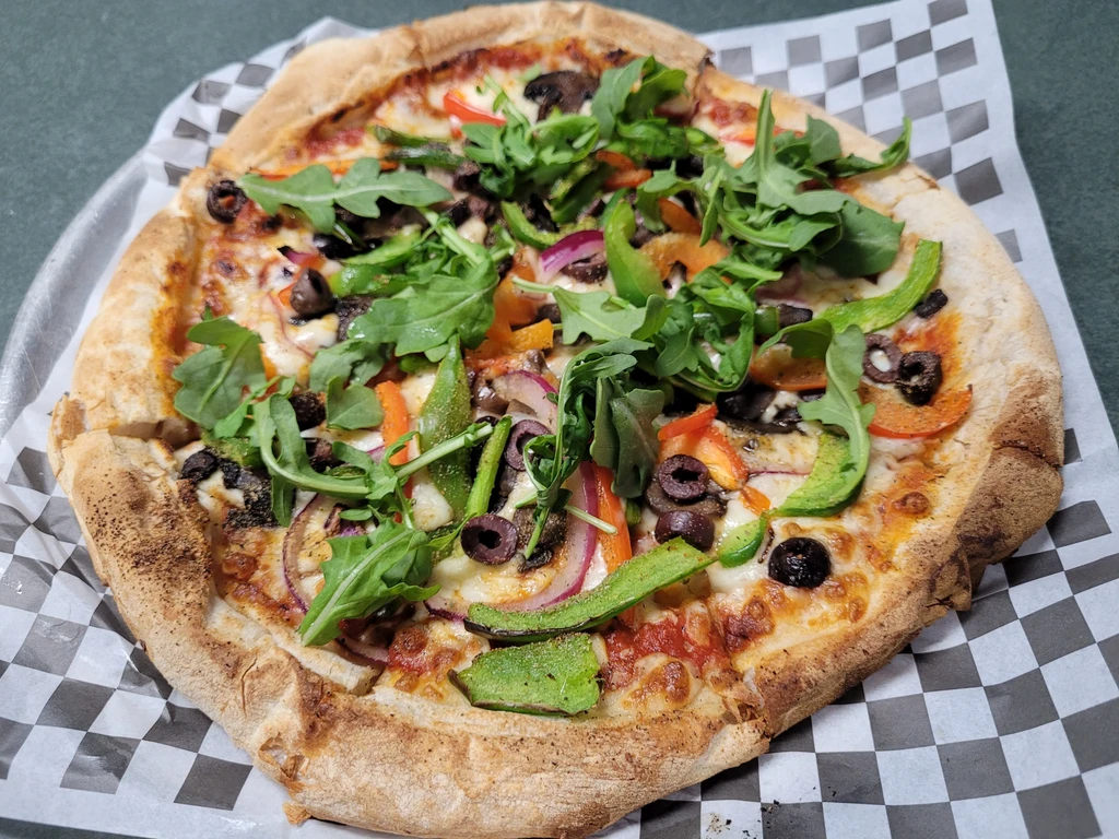 Whole pizza topped with colorful vegetables, olives, and mushrooms.