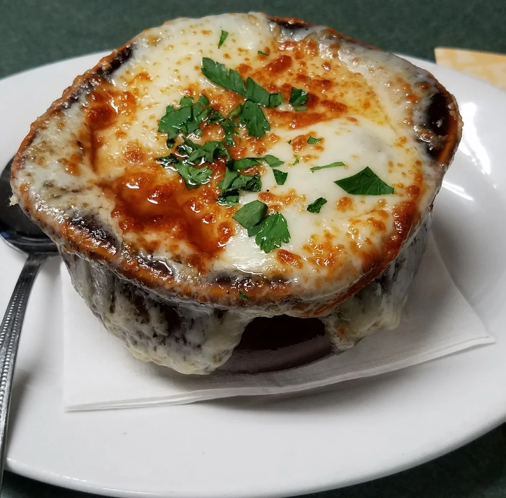 French onion soup overflowing with crisped, melted cheese and fresh herbs.