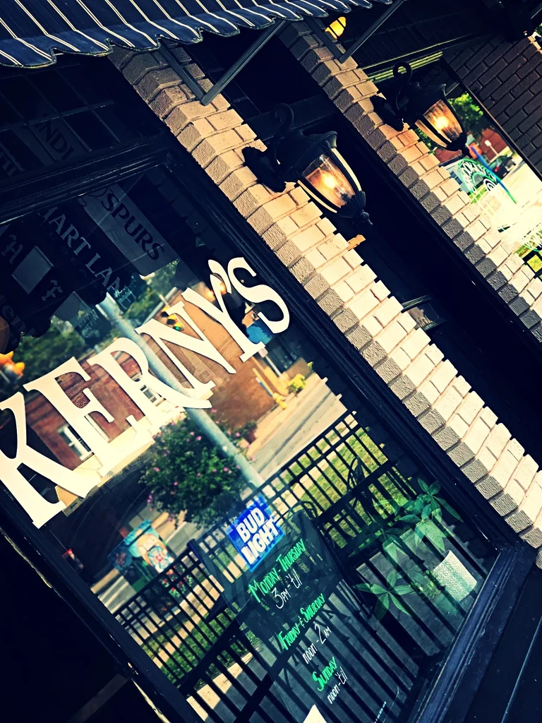 Angled view of REDDY'S storefront with striped awning and illuminated lanterns.