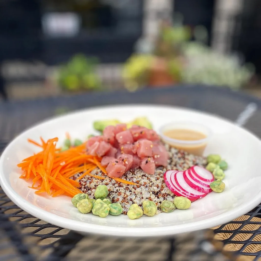 Poke bowl with raw fish, mixed grains, and various vegetables.