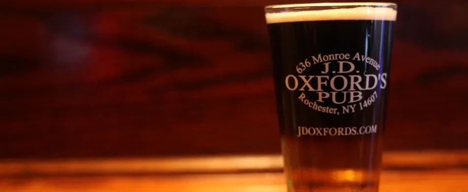 Pint of dark beer with thick foam, J.D. Oxford's Pub on glass.