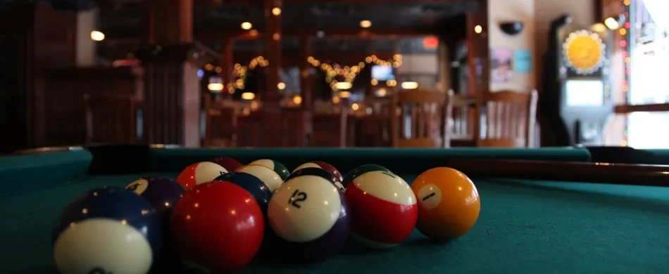 Racked billiard balls and cue on a green pool table.