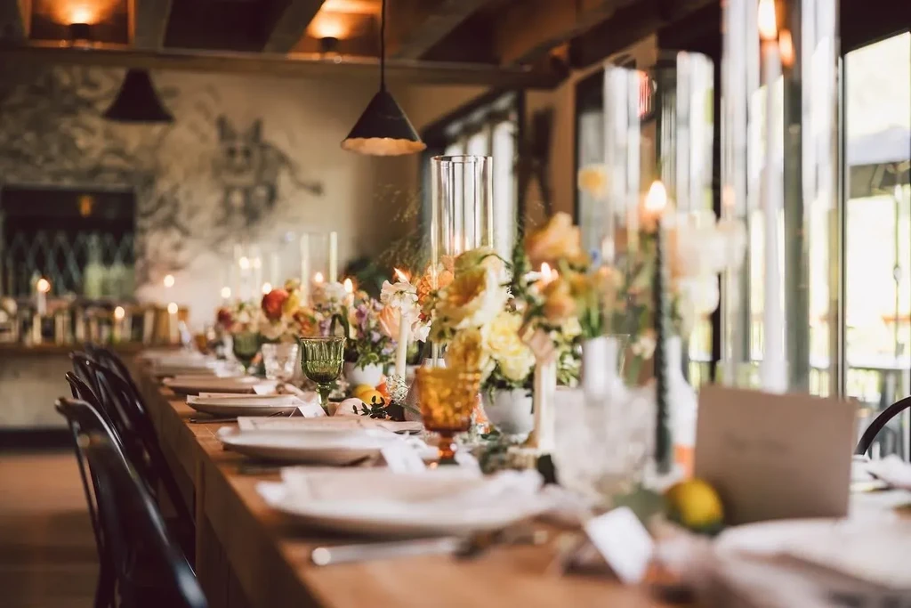 Elegant dining table decor with colorful flowers, candles, and ornate glasses.