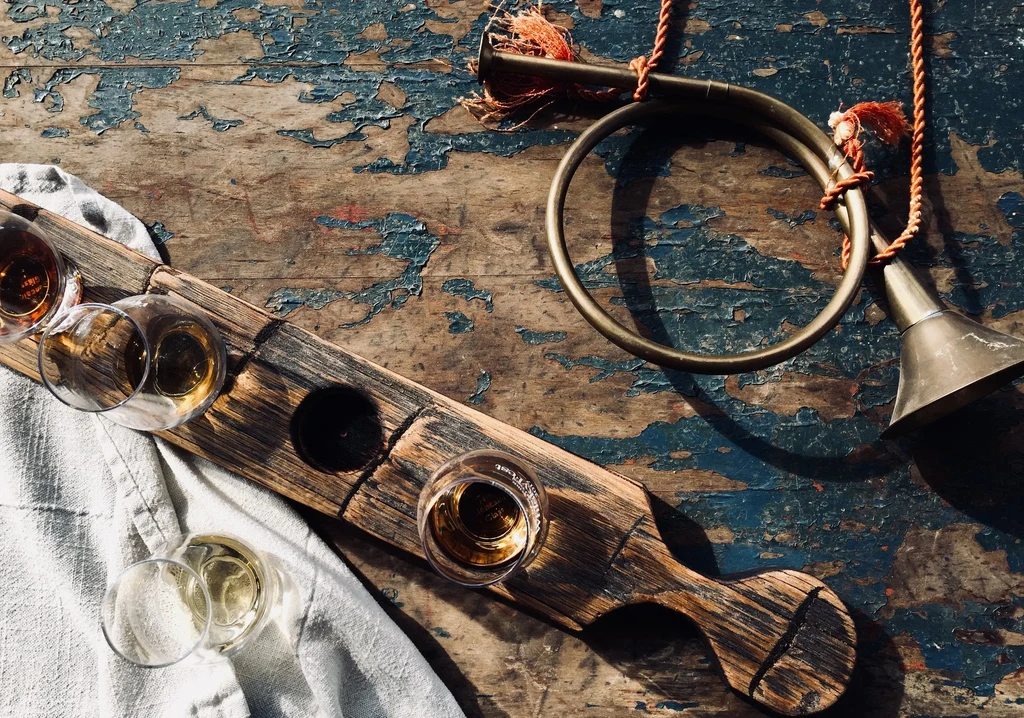 Rustic flight board with amber drinks, antique horn, distressed blue wood.