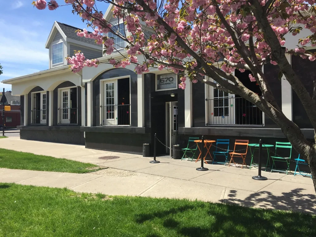 Restaurant exterior with colorful outdoor tables and pink cherry blossoms.