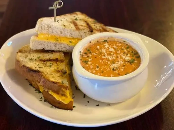 Grilled cheese sandwich and tomato soup with cheese and herbs.