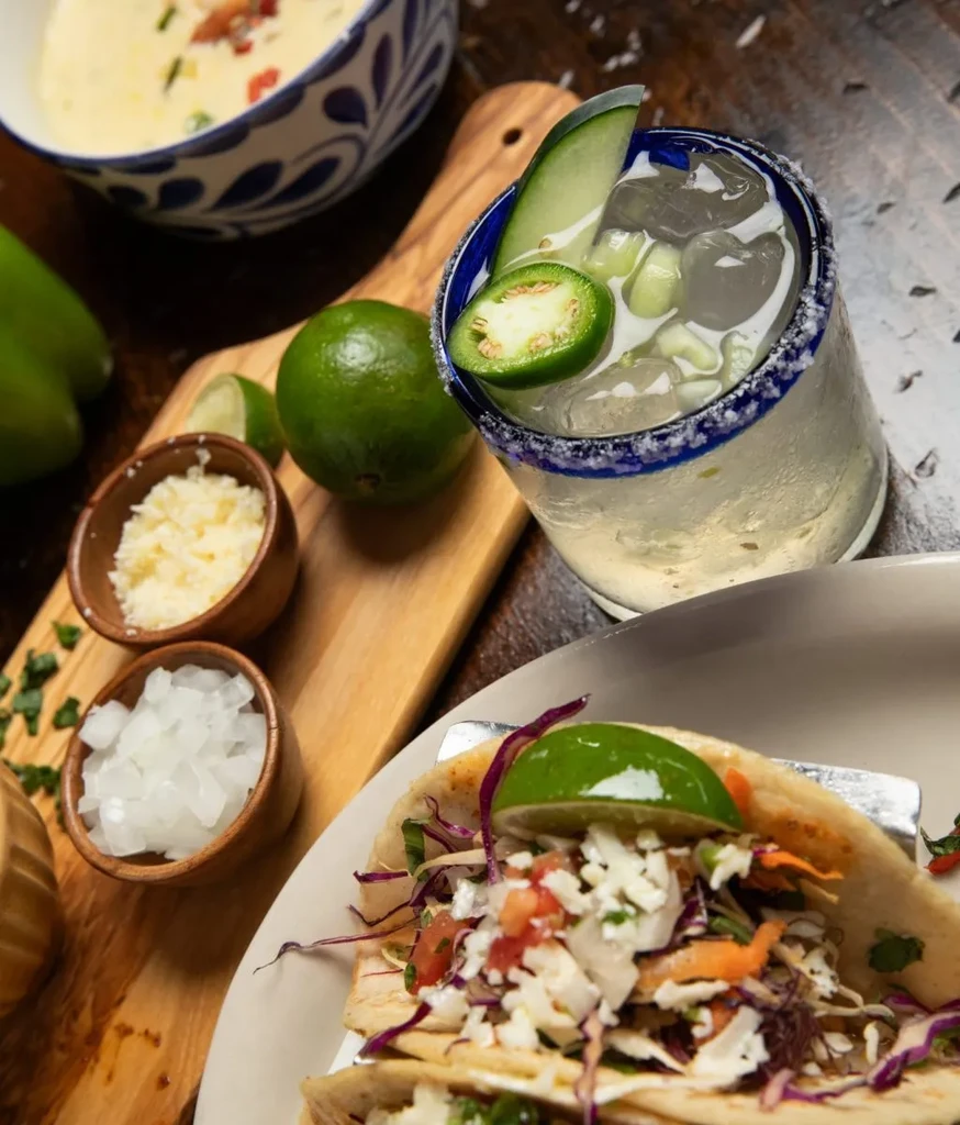 High-angle shot of Mexican-inspired tacos, soup, and drink on a table.