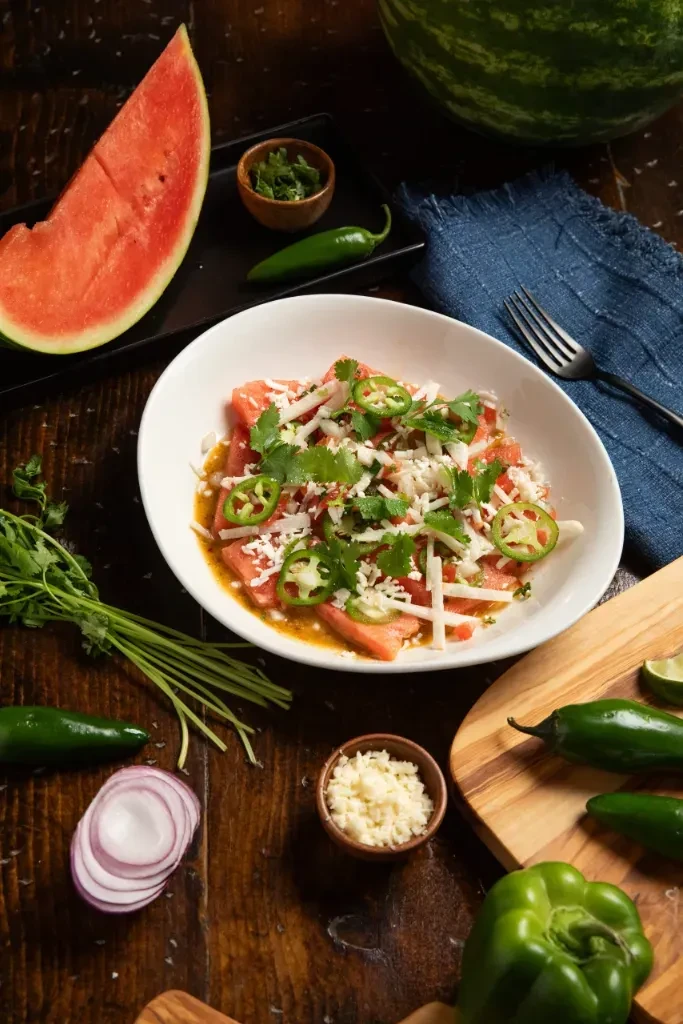 Overhead view of a watermelon salad and fresh ingredients.