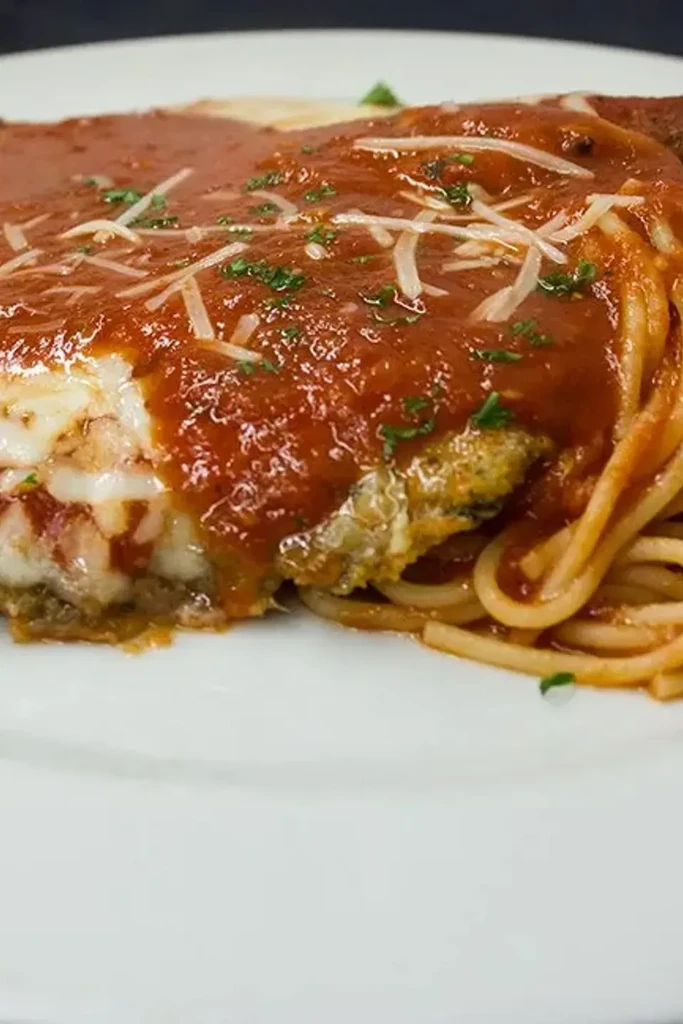 Chicken or eggplant parmesan with marinara sauce, melted cheese, and spaghetti.