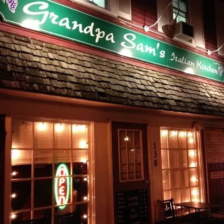 Night view of Grandpa Sam's Italian Kitchen, with green sign and warm lights.
