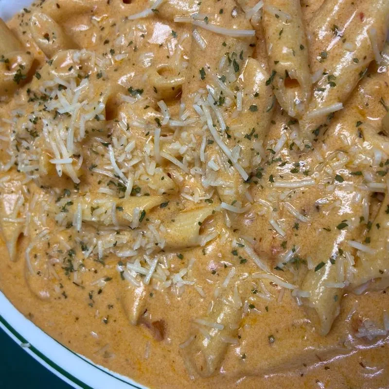 Penne pasta in creamy orange sauce topped with cheese and herbs.
