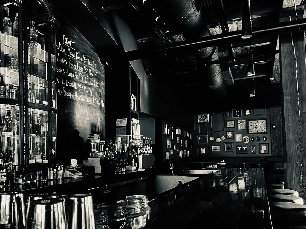 Dark, moody, industrial-chic bar interior with a draft menu.