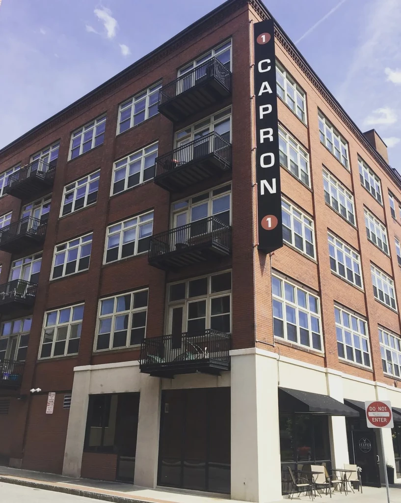 Urban multi-story brick building with '1 CAPRON 1' and 'VESPER' signs.