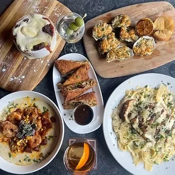 Overhead view of a table with diverse restaurant dishes and cocktails.