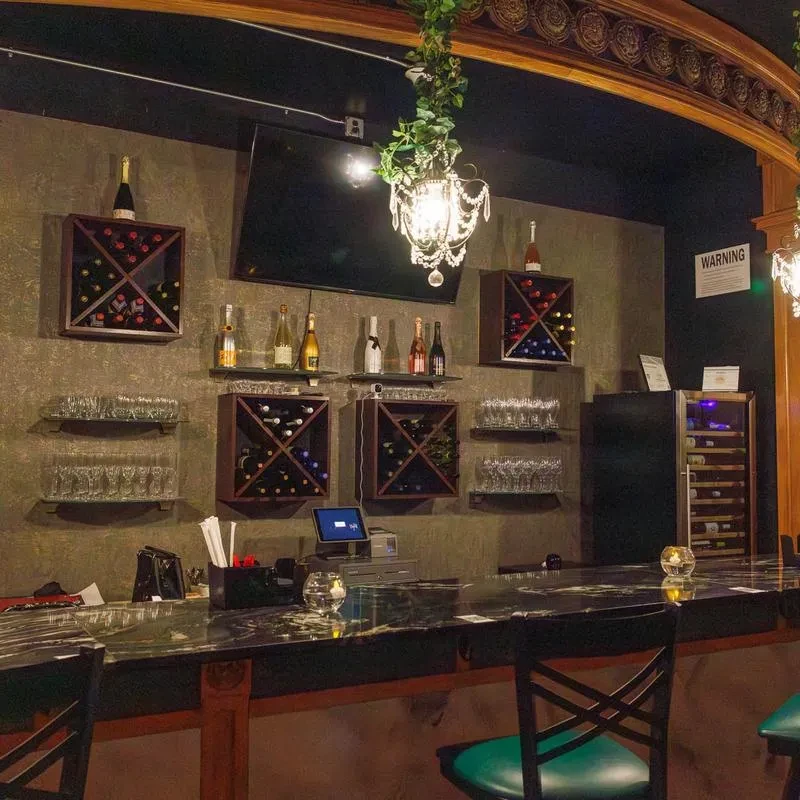 Dimly lit bar with a dark counter and intricate wine display.