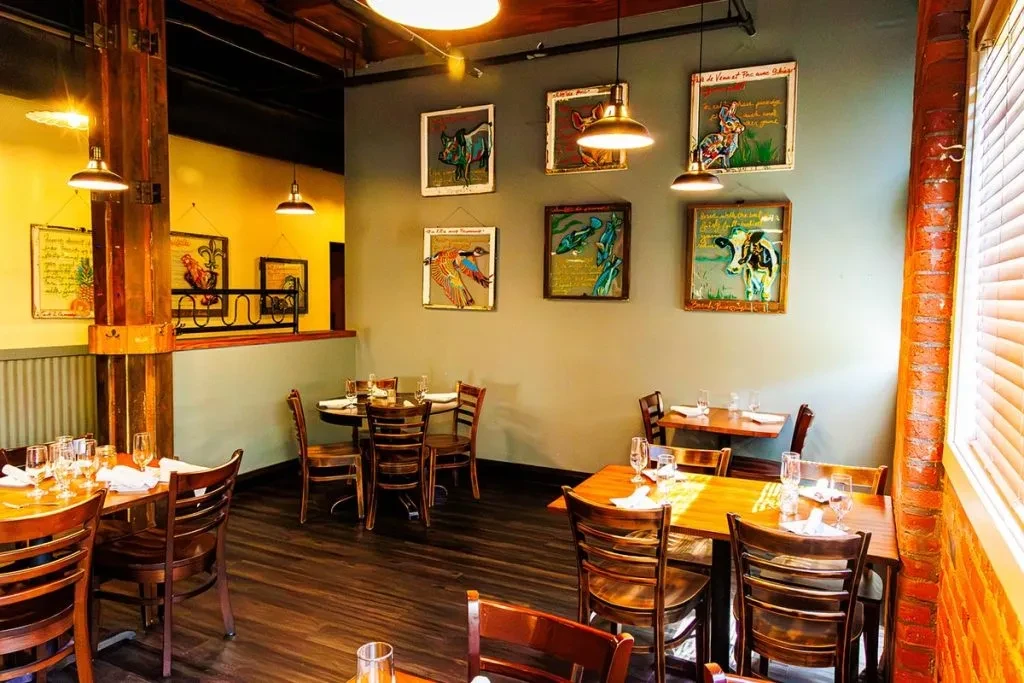 Warm restaurant dining room with wooden tables, animal art, and exposed beams.