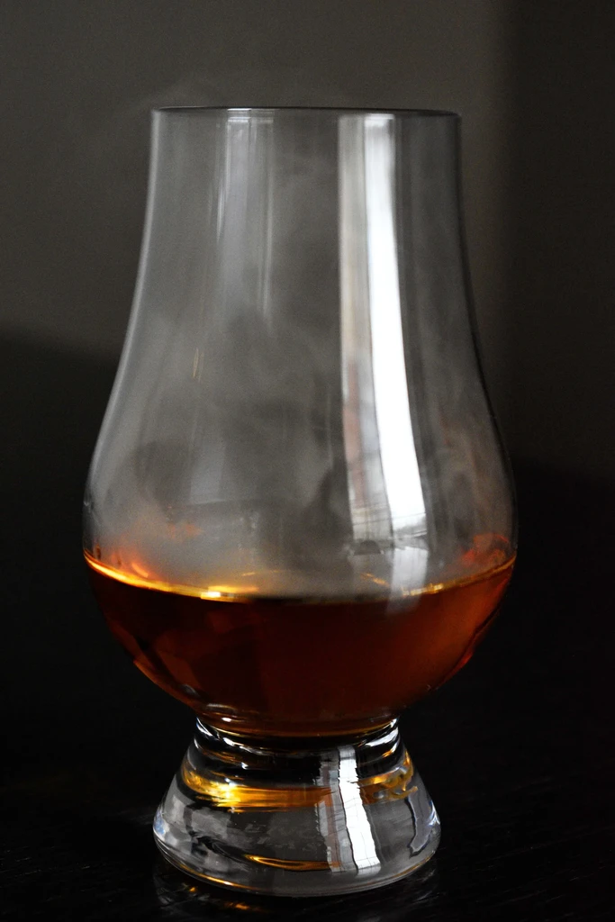 Glencairn glass with amber whiskey and a wispy smoke effect.