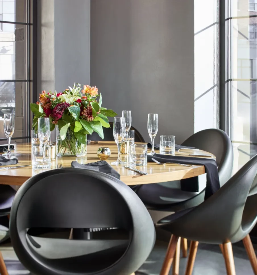 Modern restaurant table with floral centerpiece, place settings, and unique chairs.