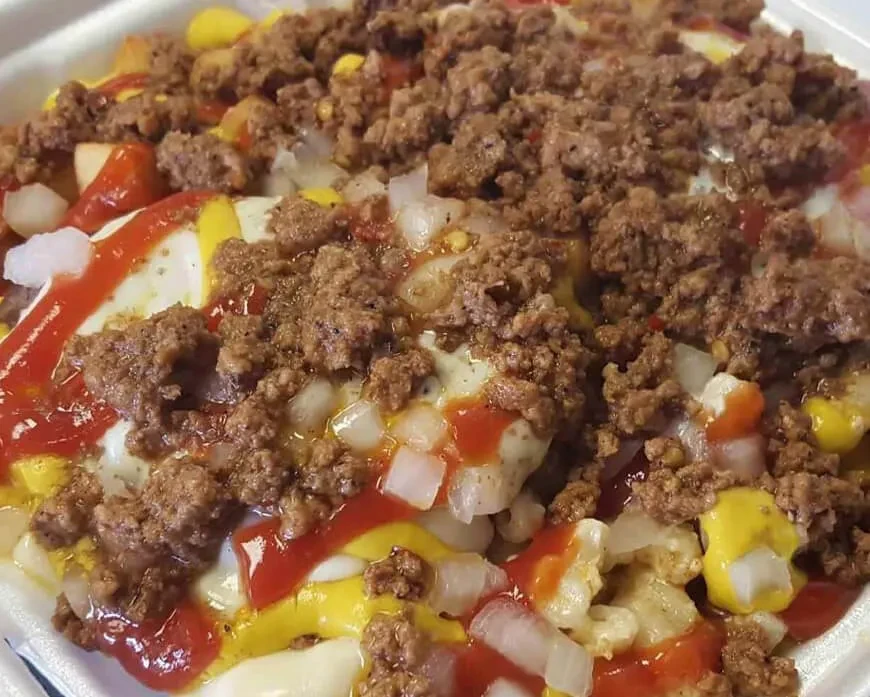 Ground meat dish with onion, mustard, and ketchup in a white container.