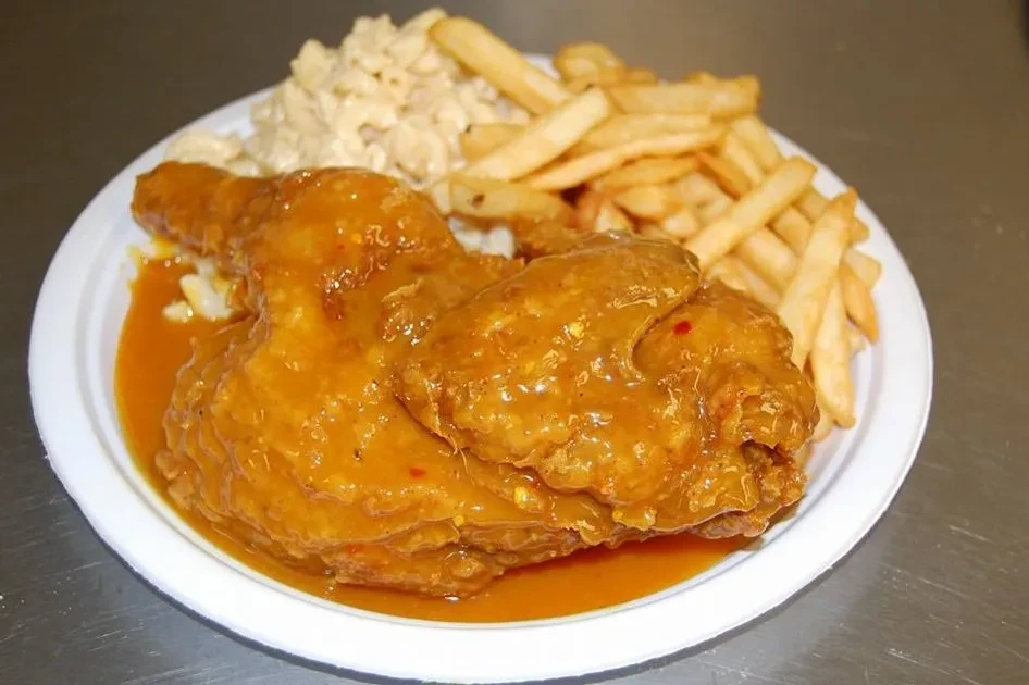 Fried chicken with spicy orange sauce, french fries, and macaroni salad.
