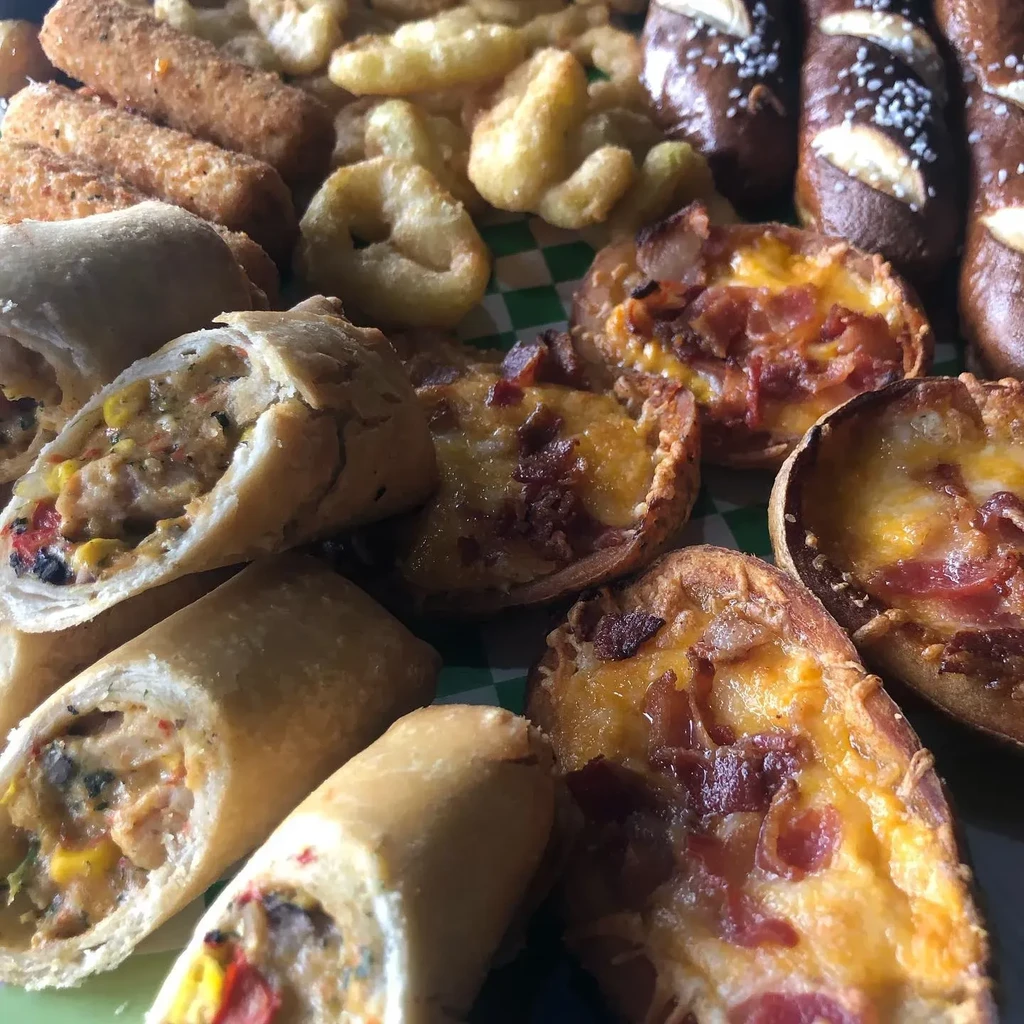 Spring rolls, potato skins, fries, pretzels, and breaded sticks on a platter.