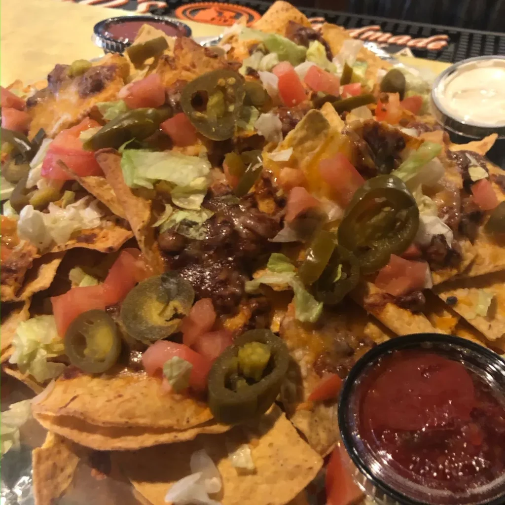 Loaded nachos topped with cheese, meat, tomatoes, and jalapeños.
