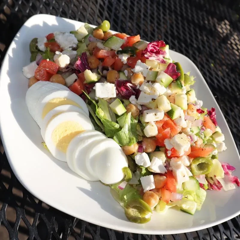 Colorful salad with hard-boiled eggs on an outdoor patio table.