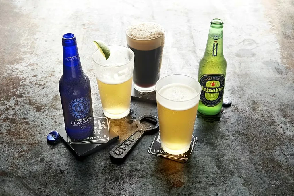 Cold beers, stout in bottles and glasses on a dark surface.
